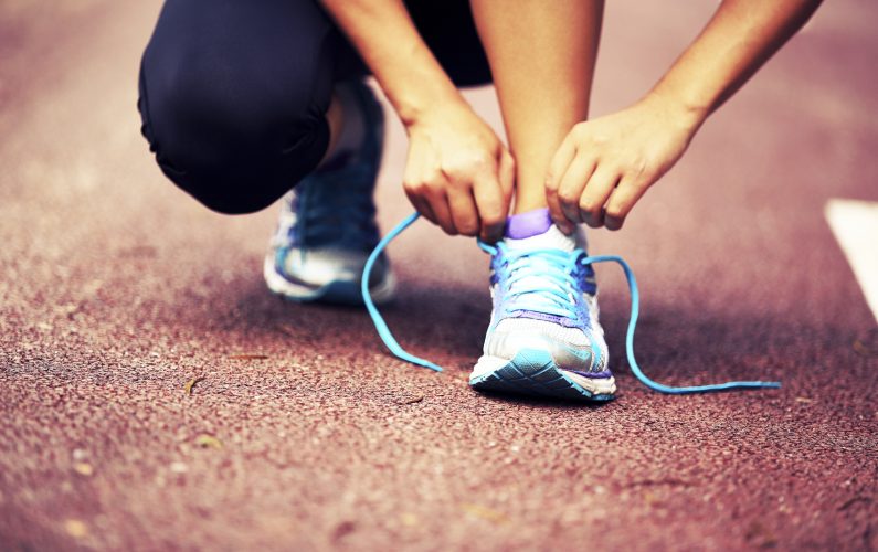 young fitness woman runner  tying shoelaces on trail
